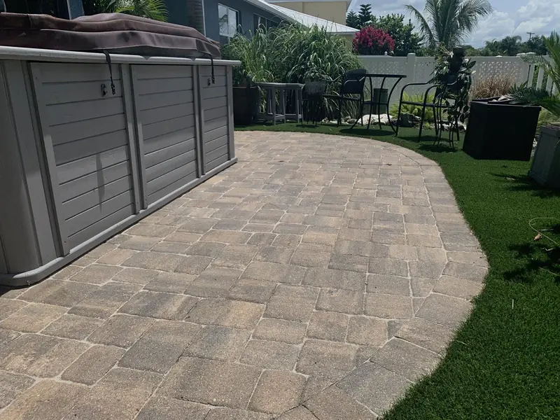 A clean paver patio beside a backyard lawn