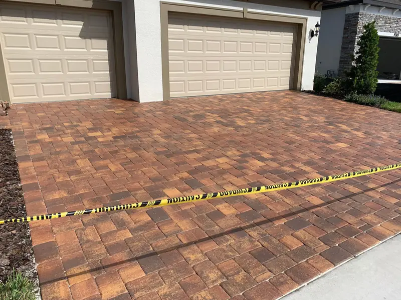 A freshly sealed paver driveway taped off while it dries